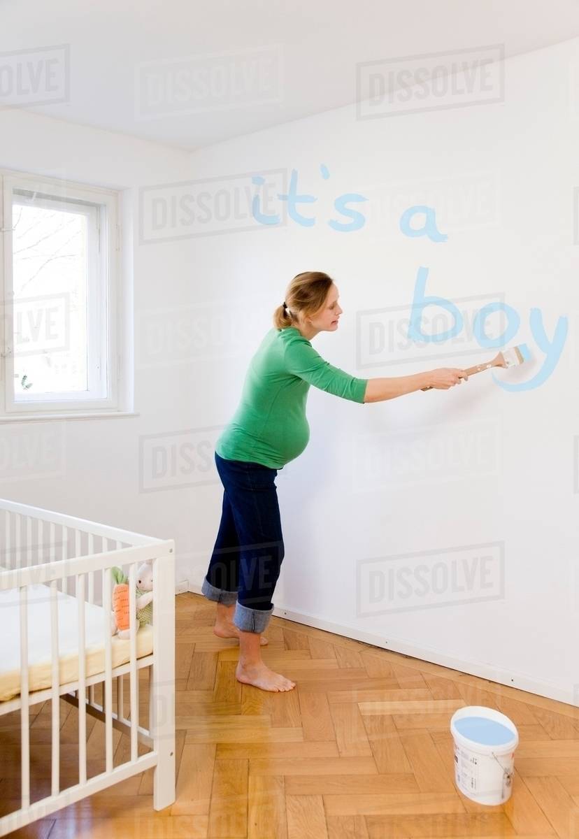 Pregnant woman painting nursery Stock Photo Dissolve