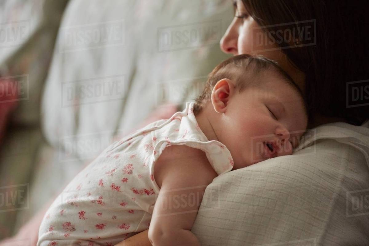 Mother carrying sleeping baby Stock Photo Dissolve