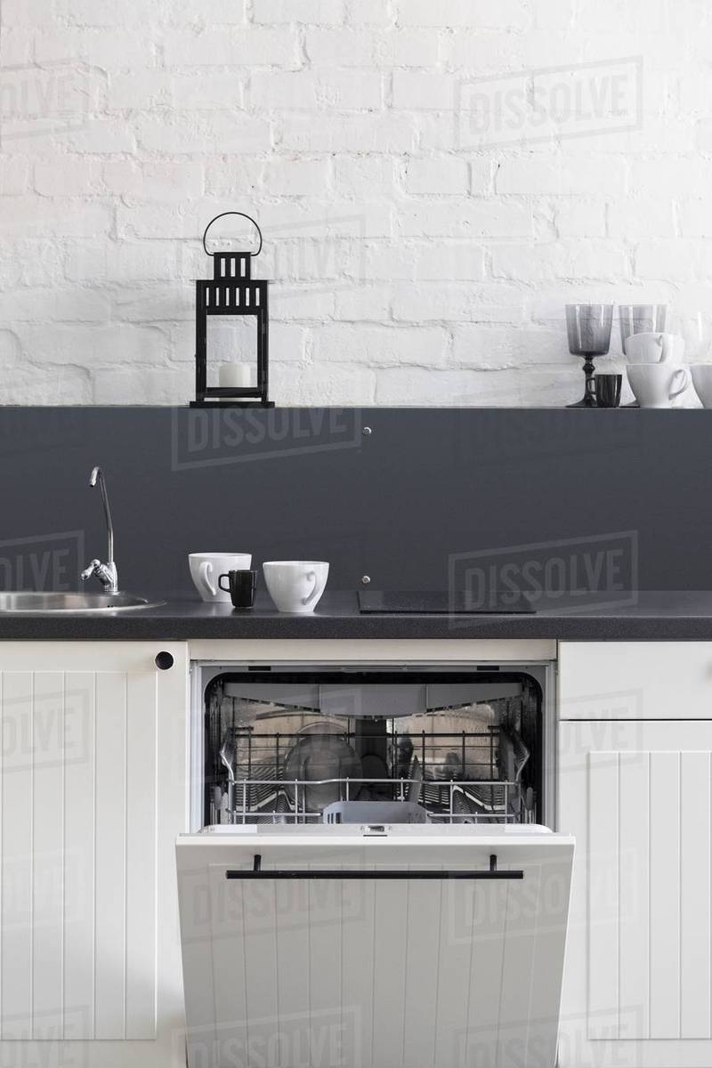 Cups on kitchen counter above dishwasher Stock Photo Dissolve