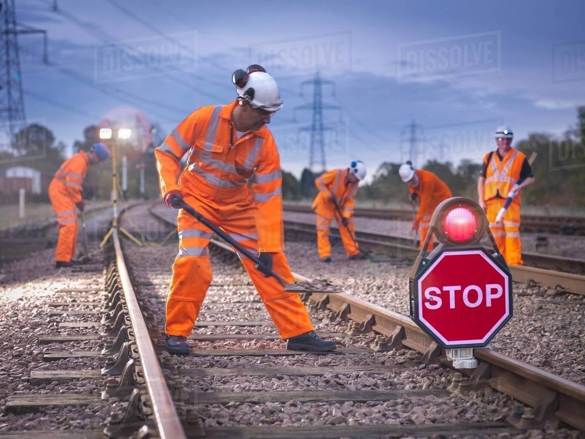 Railway maintenance workers on track with stop sign at night Stock