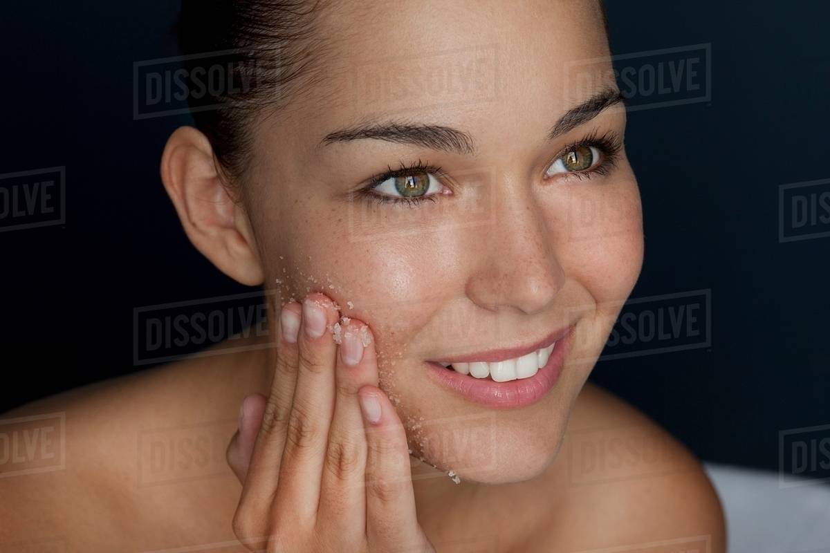 Woman scrubbing her face with sugar Stock Photo Dissolve