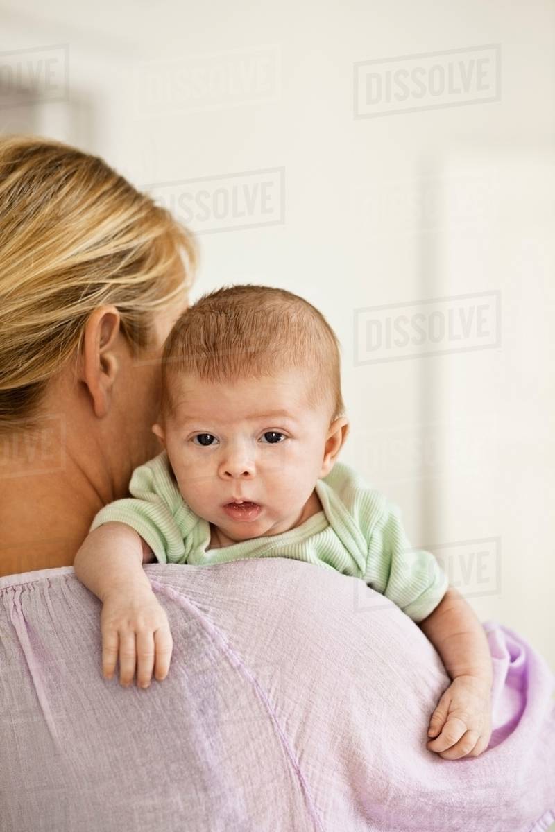 Mother cradling infant on shoulder Stock Photo Dissolve