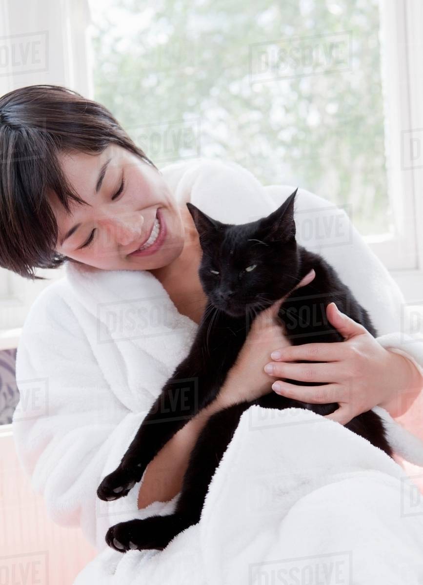Woman in bathrobe holding cat Stock Photo Dissolve
