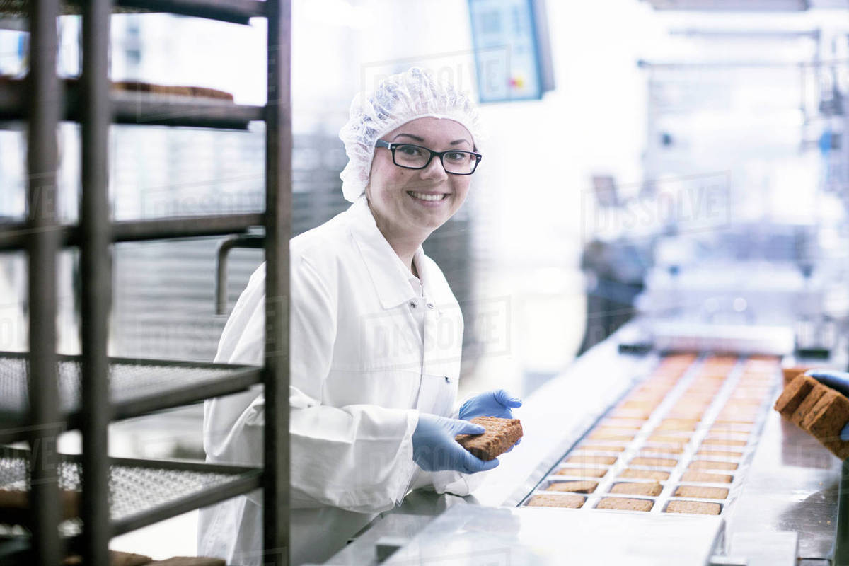 Factory worker on food production line looking at camera smiling