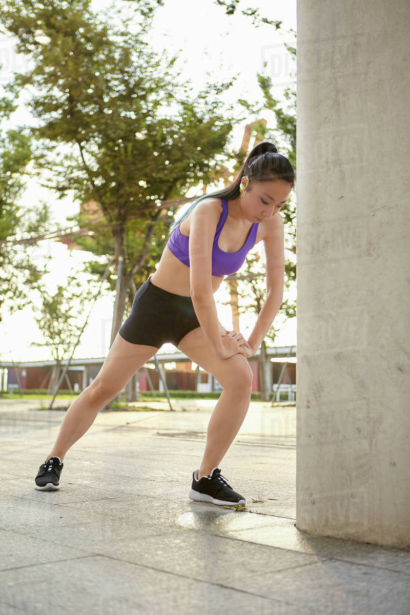 Young woman wearing spandex stretching leg Stock Photo Dissolve