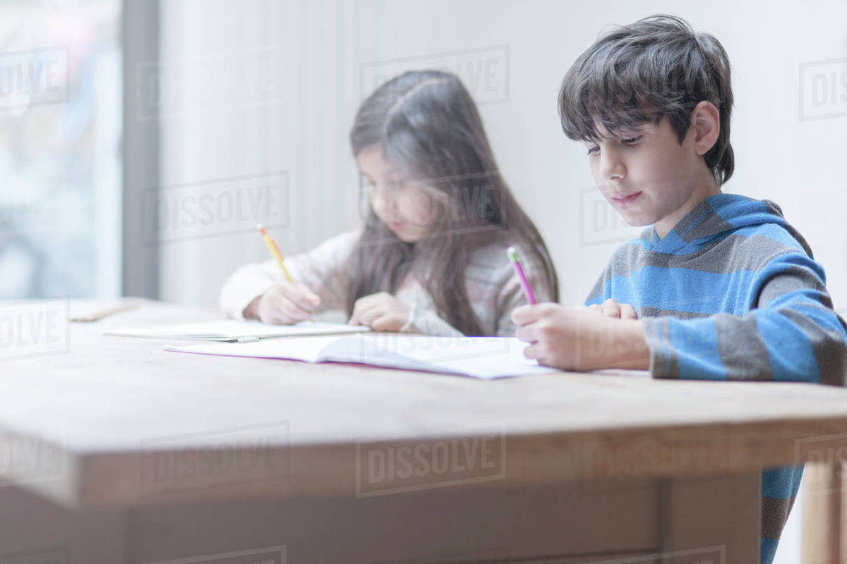 Boy and sister doing homework at kitchen table Royalty-free stock photo