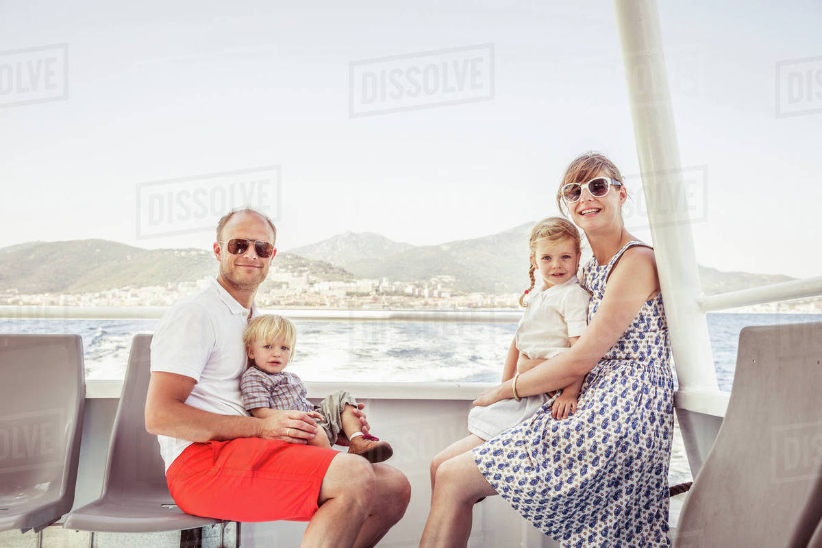 Portrait of family sitting on boat, smiling - Stock Photo - Dissolve