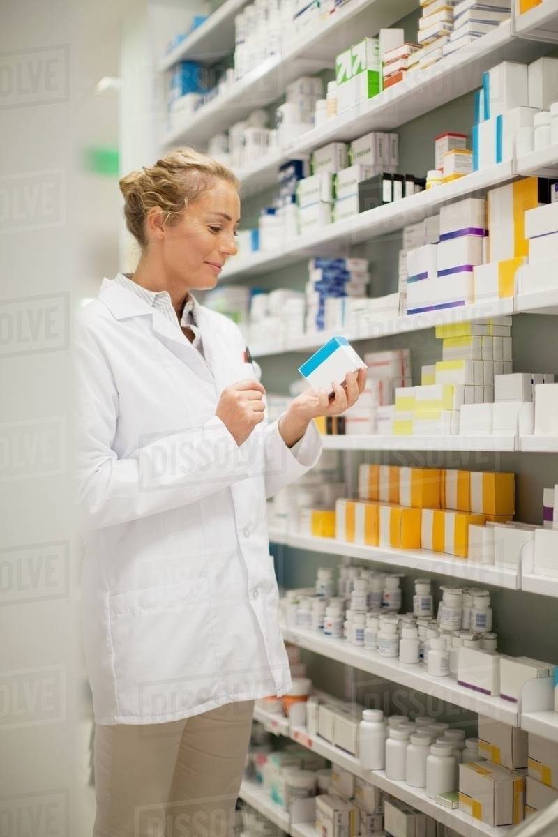 Pharmacist browsing medicines on shelf Stock Photo Dissolve