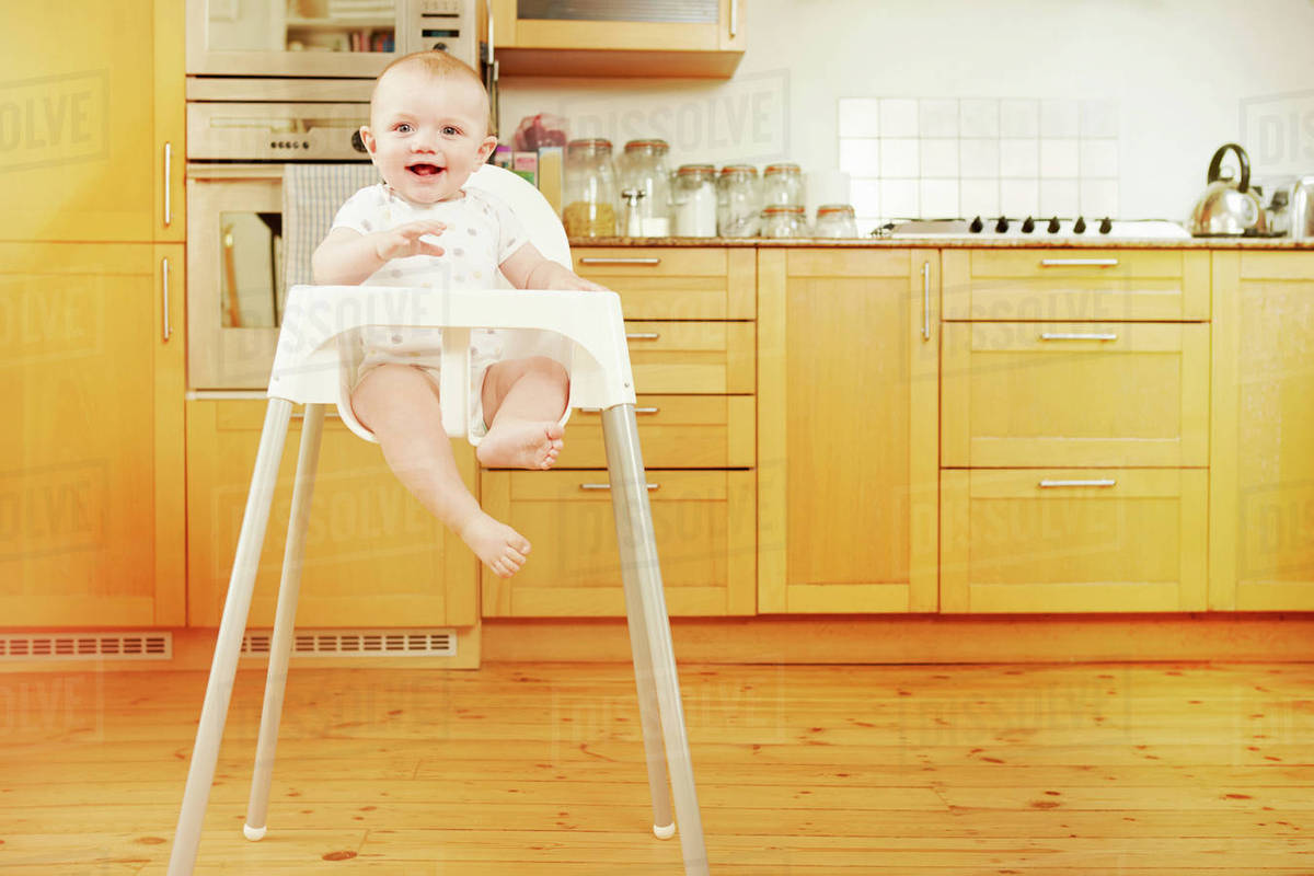 Baby boy sitting in high chair Stock Photo Dissolve