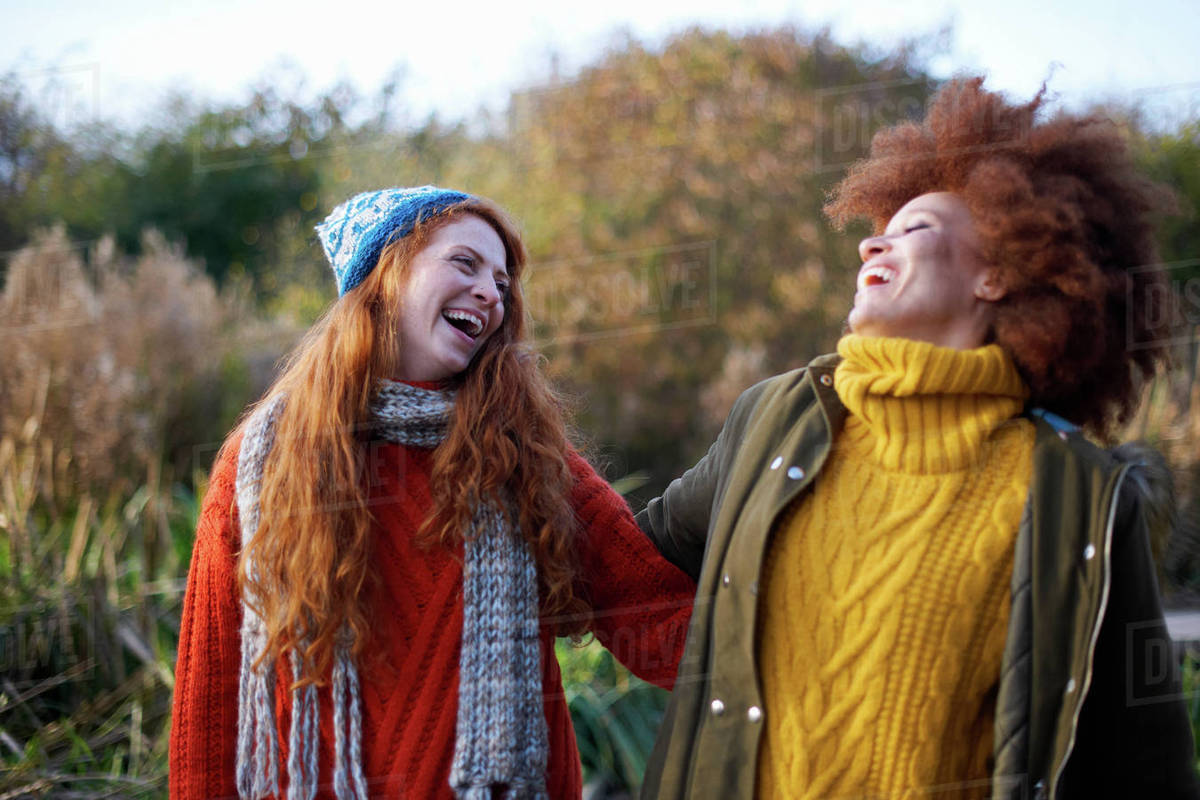 Friends arm in arm throwing head back laughing Stock Photo Dissolve