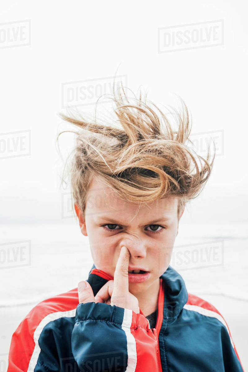 Portrait Of Boy On Beach Messy Hair Poking Finger Up Nose Close