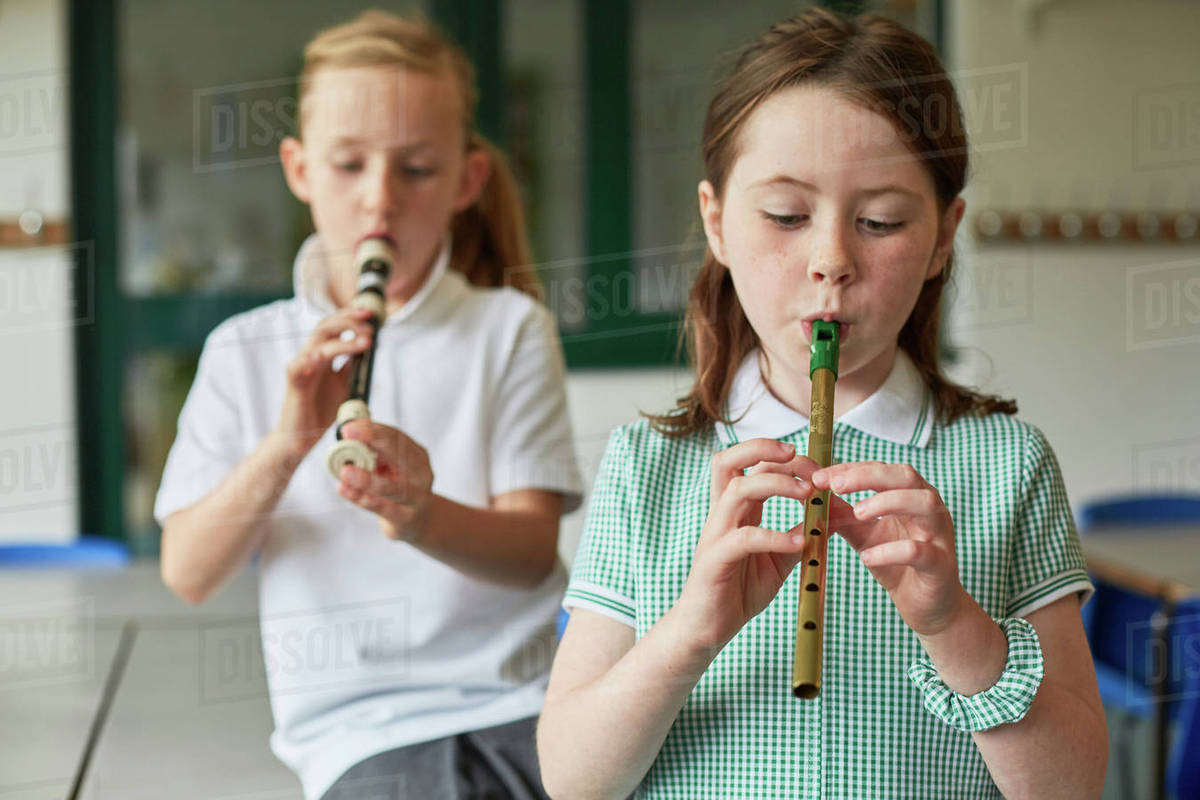 Schoolgirls playing recorders in classroom at primary school Stock