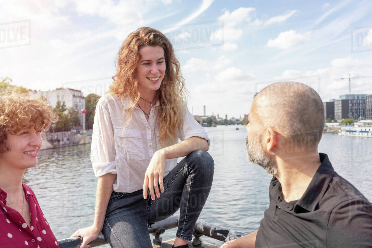 Man and female friends talking, river in background, Berlin, Germany ...