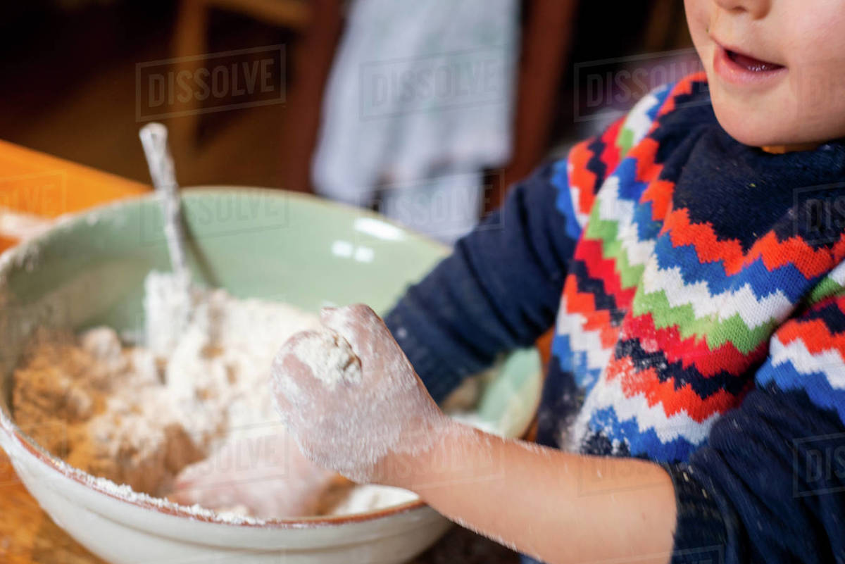 Toddler playing with flour in mixing bowl Stock Photo Dissolve