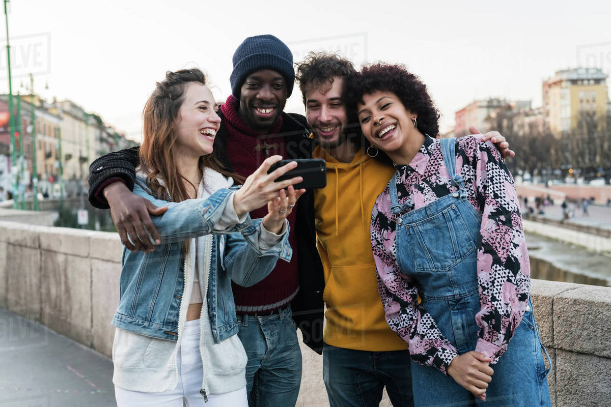 Four female and male young adult friends taking selfie on city canal waterfront Royalty-free stock photo