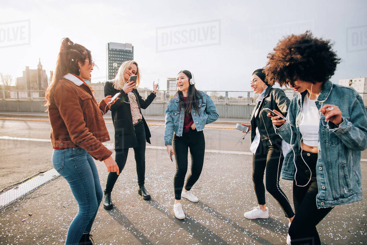 Friends dancing in street to smartphone music, Milan, Italy Stock