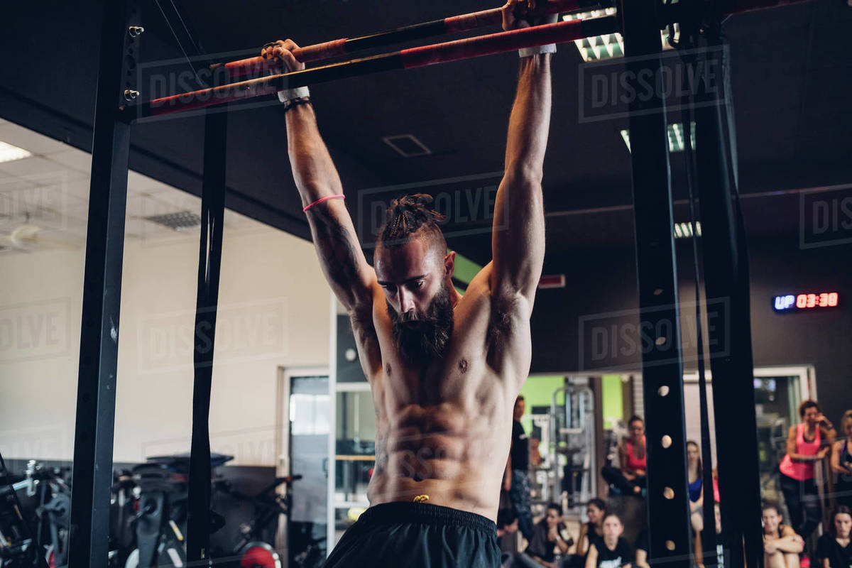 Young man training in gym, swinging on exercise bar Stock Photo