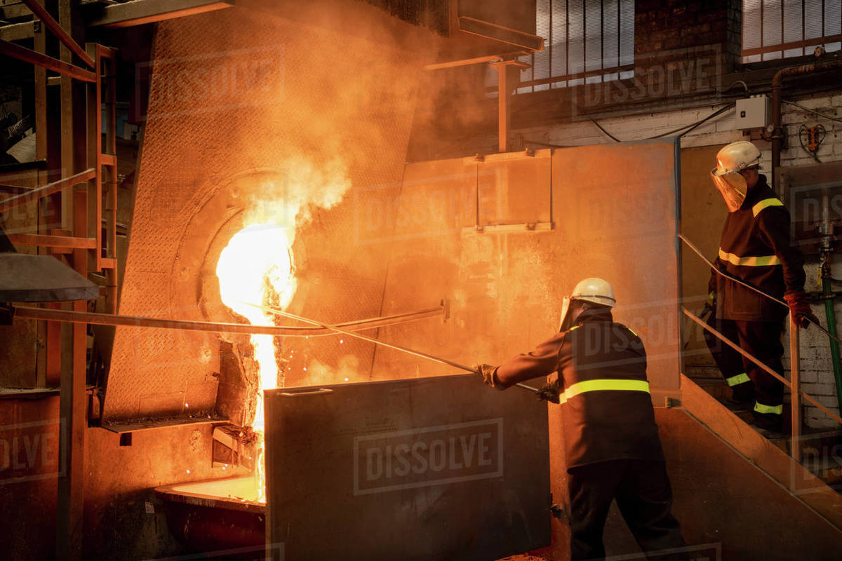 Workers pouring liquid titanium alloy from furnace in titanium recycling plant Royalty-free stock photo