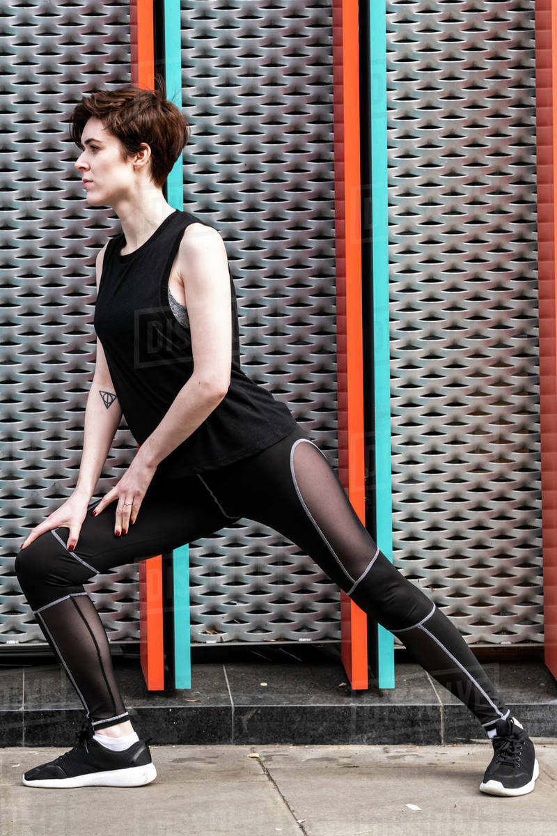 Young woman practicing yoga pose on city sidewalk, full length Royalty-free stock photo