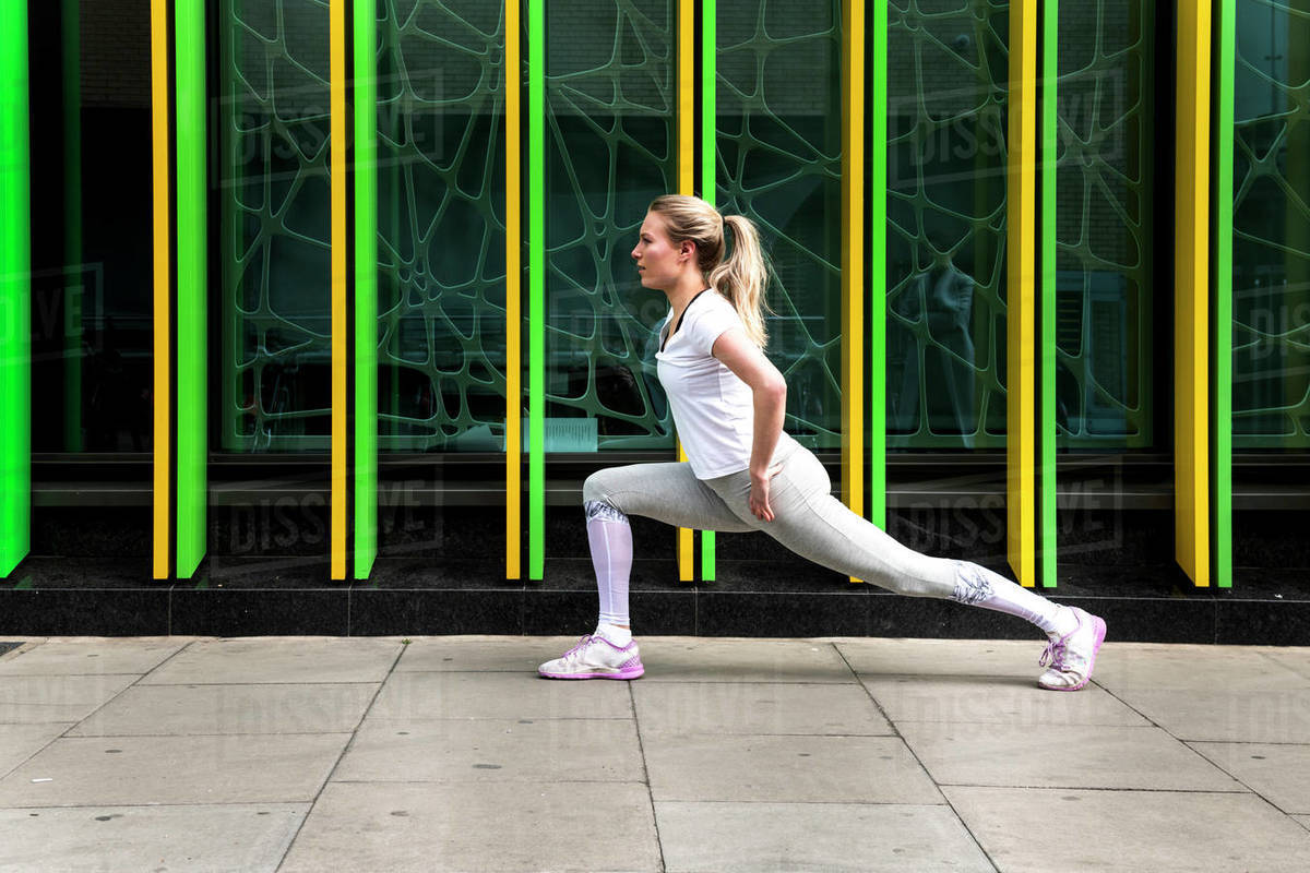 Young woman practicing yoga pose on city sidewalk, full length Royalty-free stock photo