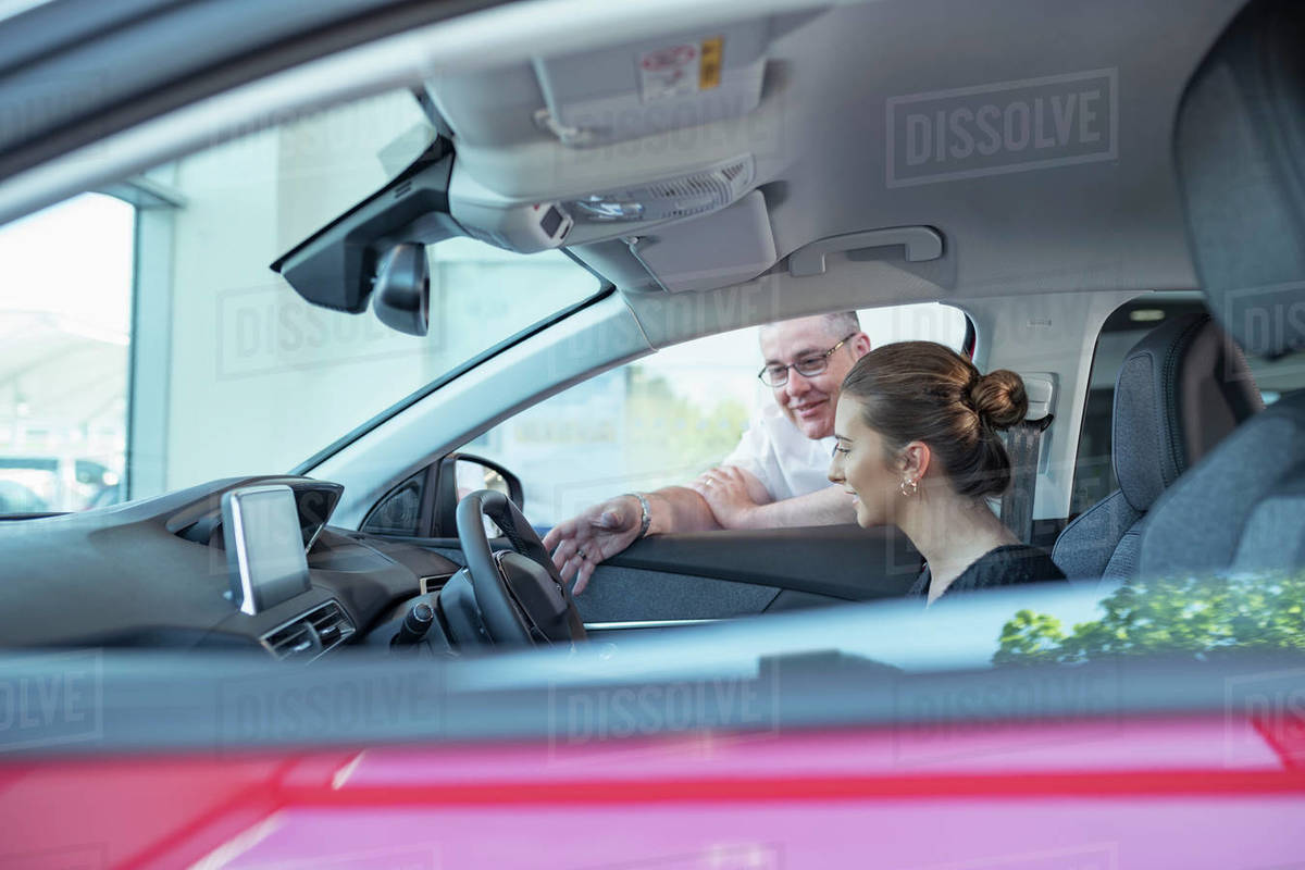 Salesman demonstrating car controls to customer in car dealership Royalty-free stock photo
