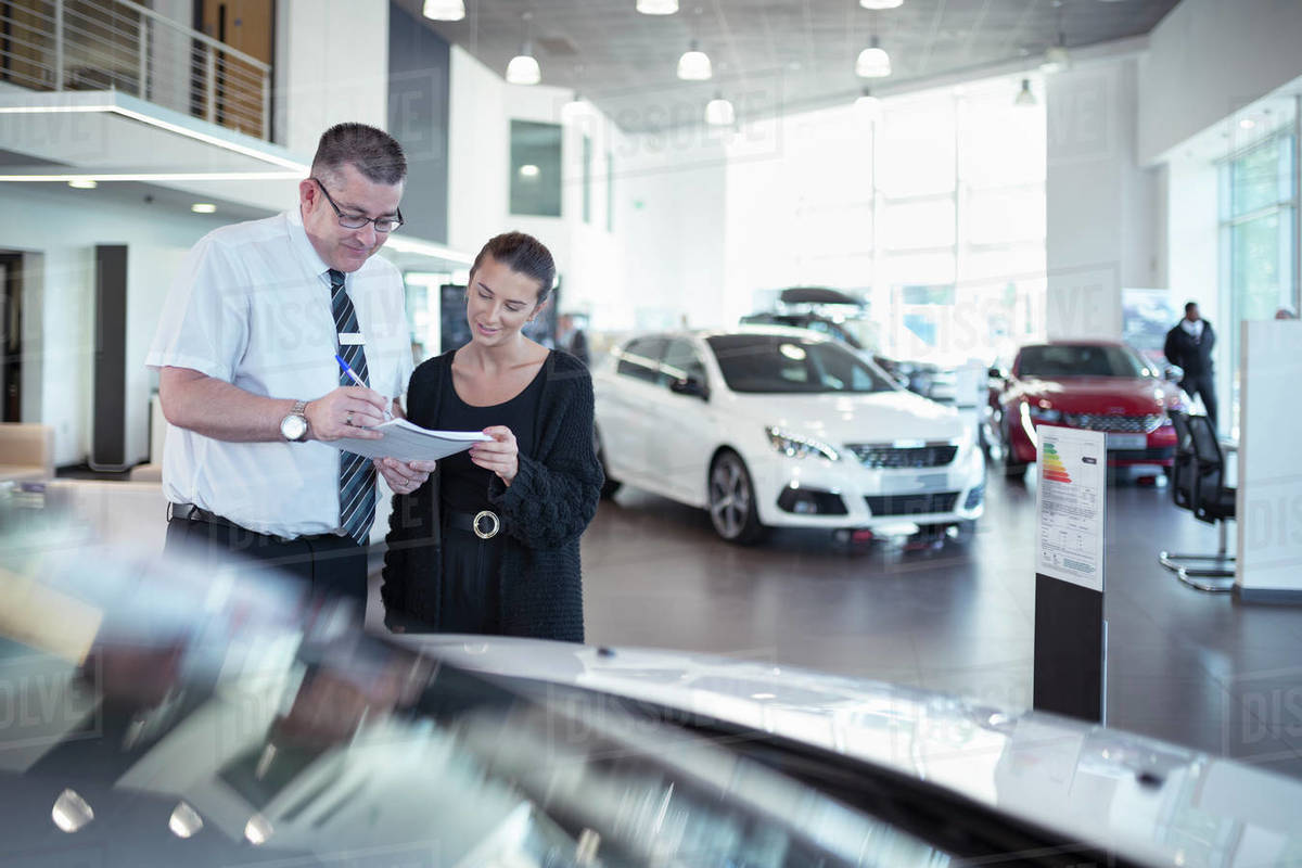 Salesman discussing contract with customer in car dealership Royalty-free stock photo