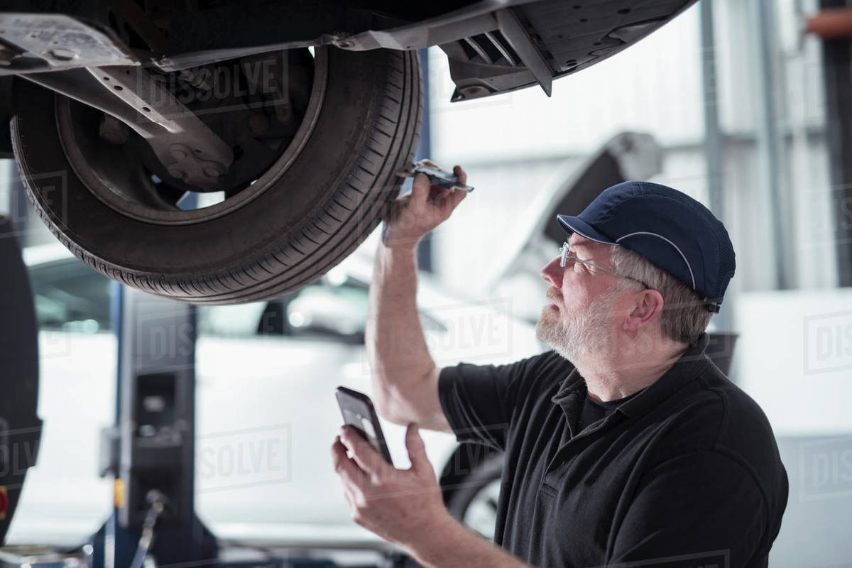 Engineer checking car tyre during service in car service centre Royalty-free stock photo