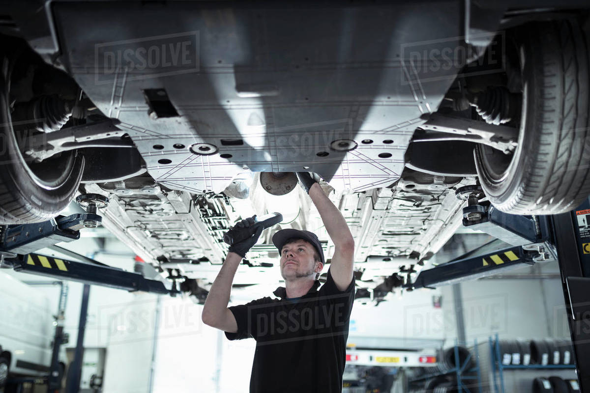 Engineer working underneath car on lift in car service centre Royalty-free stock photo