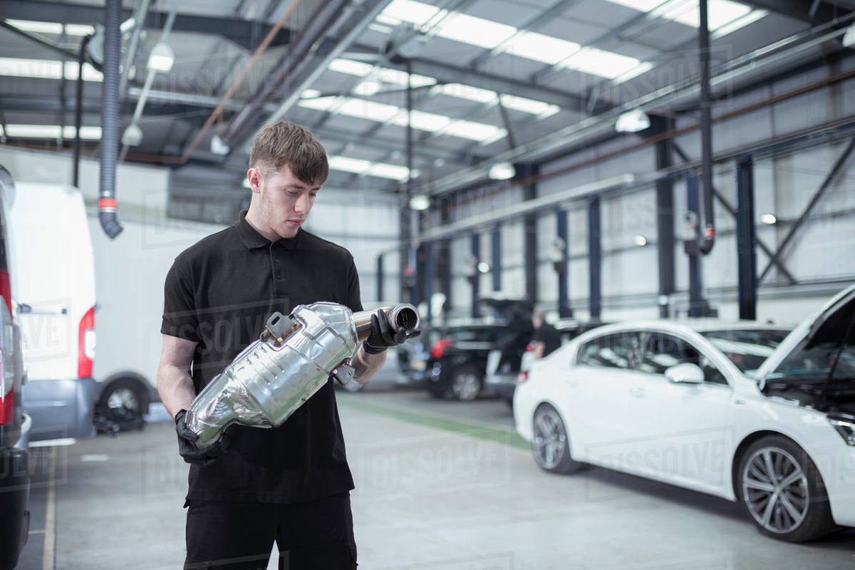 Apprentice holding catalytic converter in car service centre Royalty-free stock photo