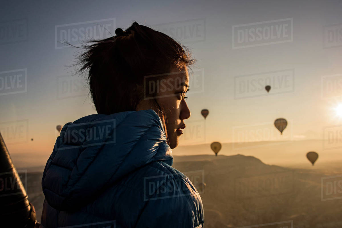 Woman enjoying view, hot air balloons flying in background, Göreme, Cappadocia, Nevsehir, Turkey  Royalty-free stock photo