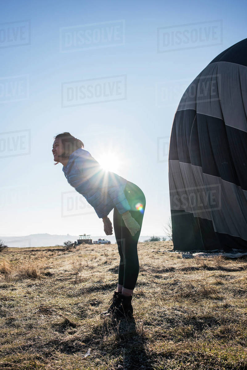 Woman bending forward against sunlight, hot air balloon in background, Göreme, Cappadocia, Nevsehir, Turkey Royalty-free stock photo