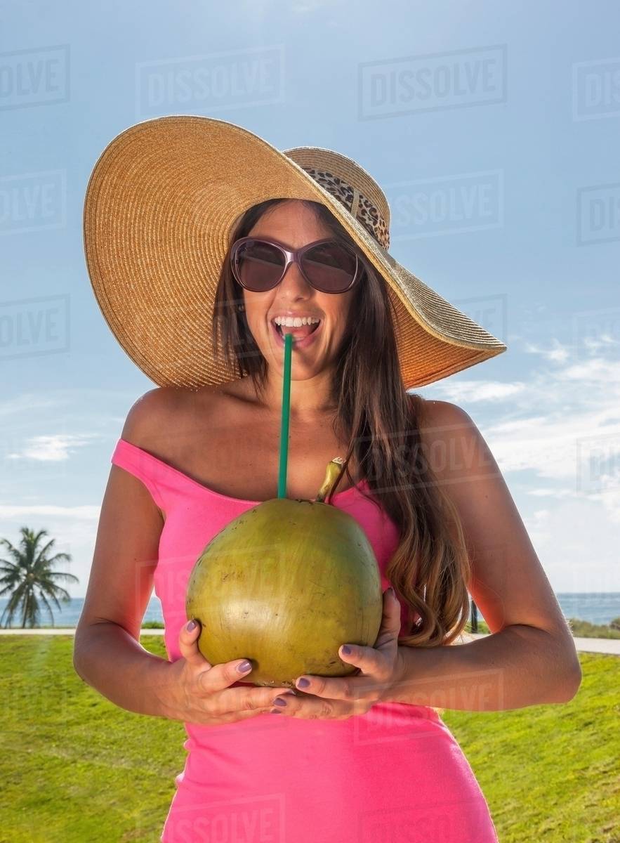 Woman drinking coconut juice with straw Stock Photo Dissolve