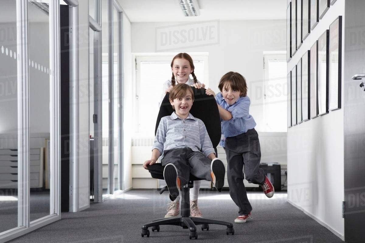 Three children playing in office corridor on office chair - Stock Photo ...