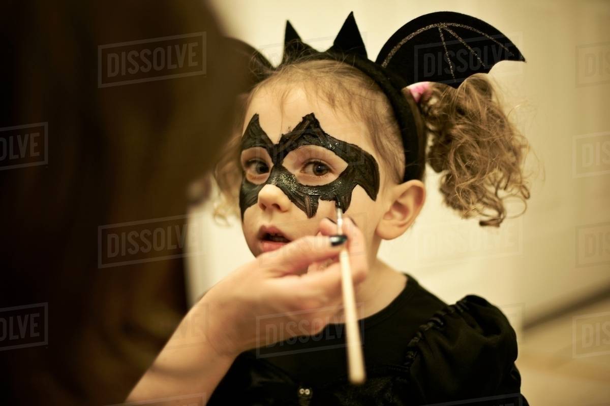 Mother painting daughters face for halloween bat costume D12_12_12