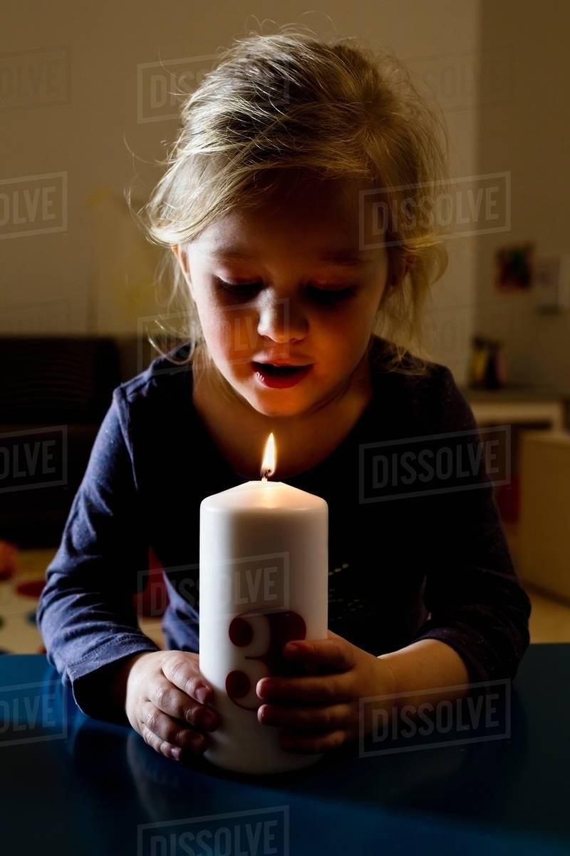 Girl holding lit candle in dark Stock Photo Dissolve