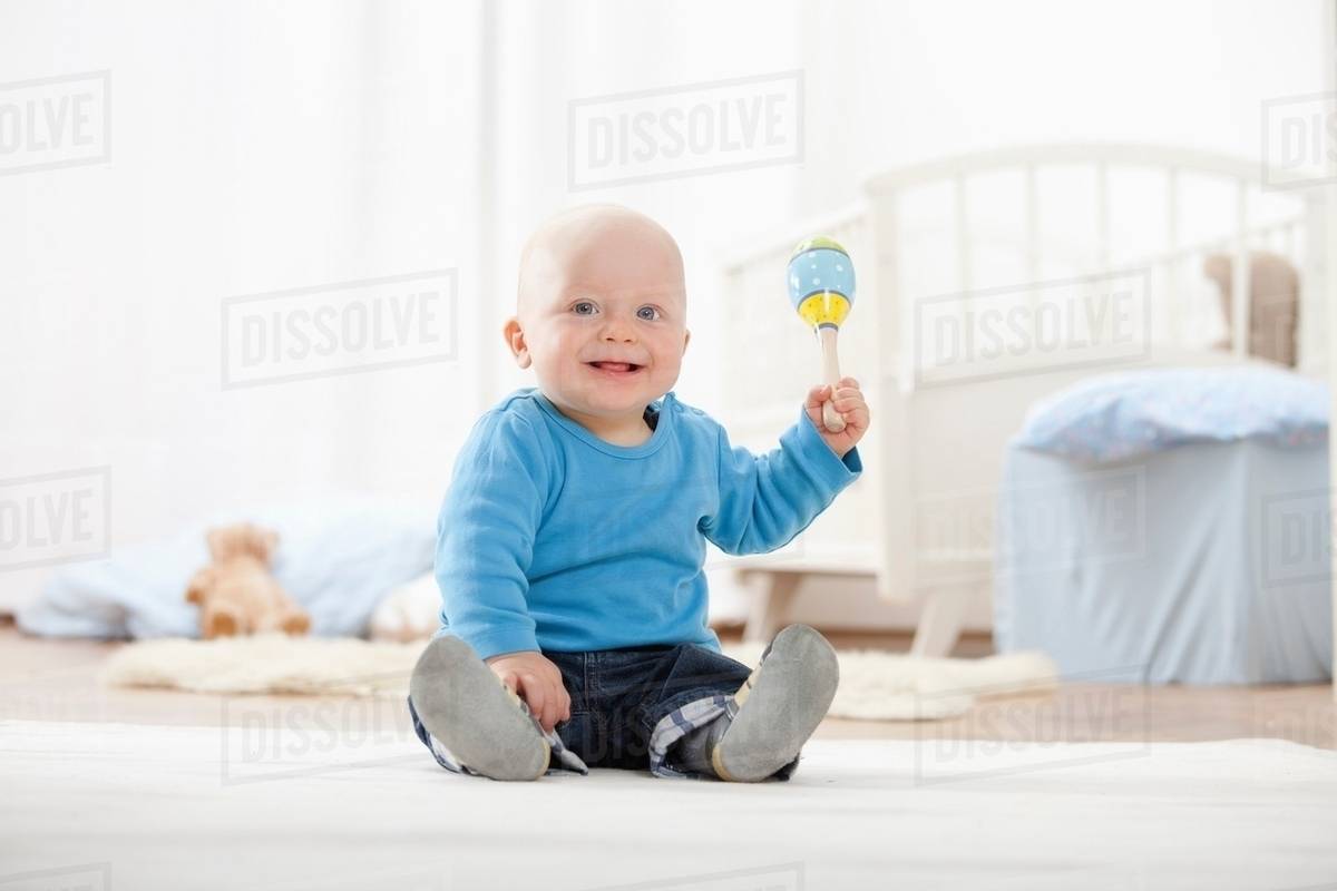 Baby boy playing with rattle Stock Photo Dissolve