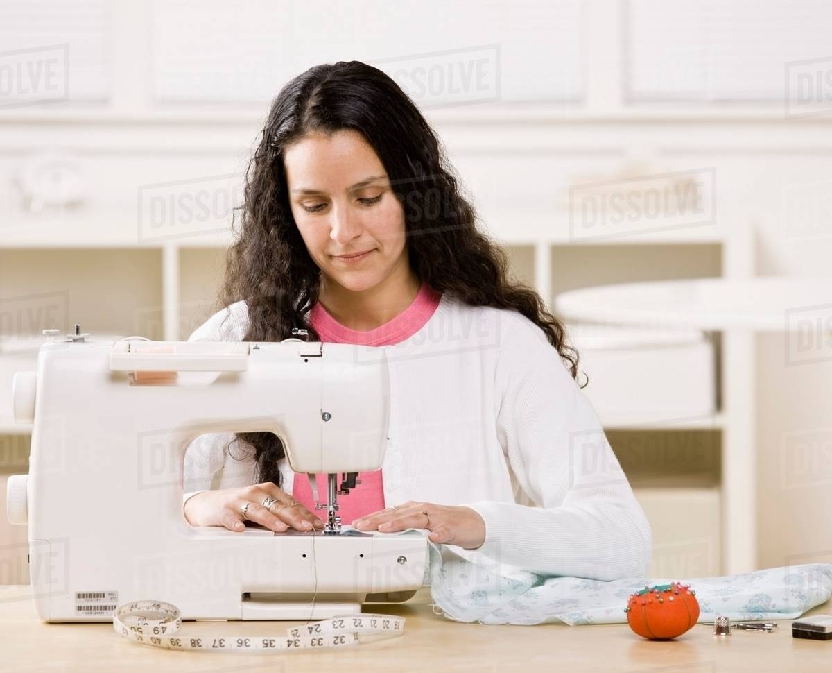 Woman using sewing machine at home Stock Photo Dissolve