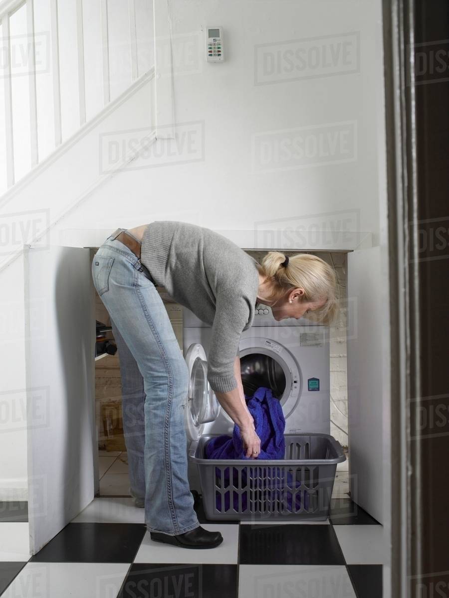 Woman unloading clothes from dryer Stock Photo Dissolve