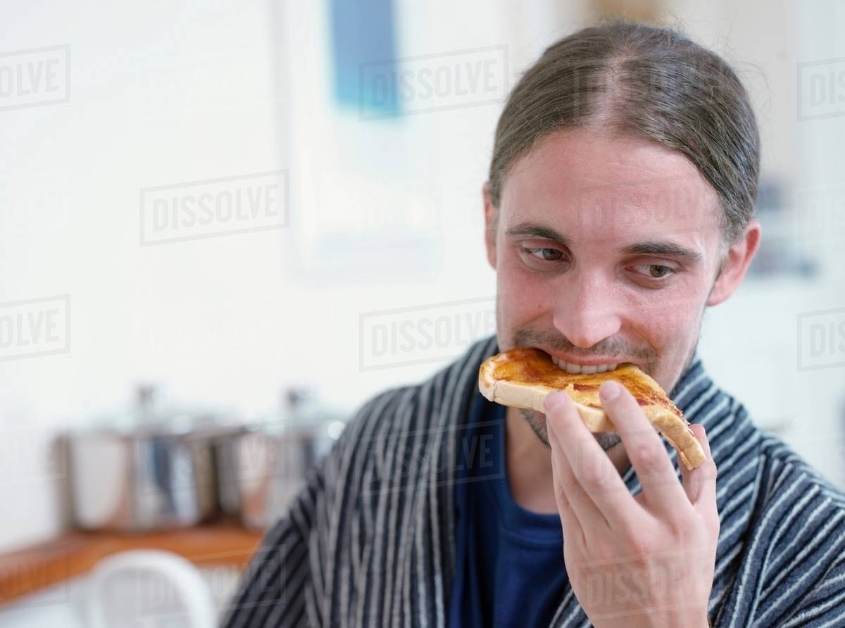 Man eating toast in kitchen Stock Photo Dissolve