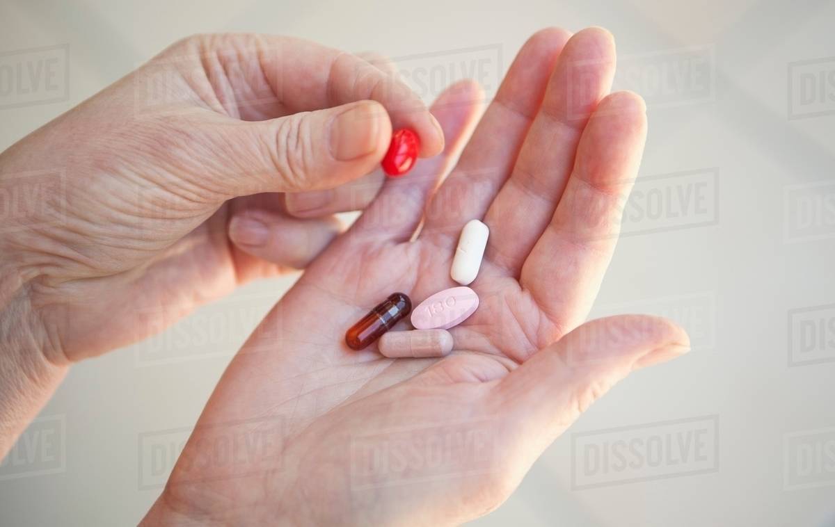 Close up of older person holding pills Stock Photo Dissolve
