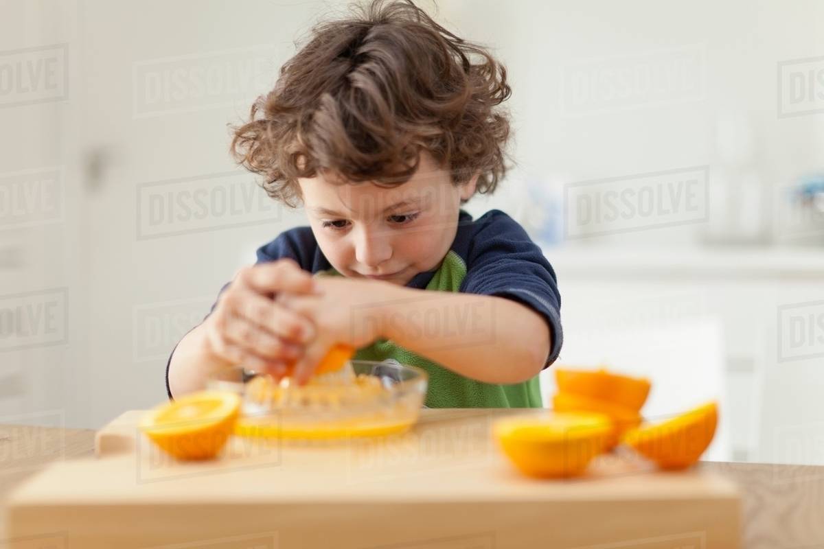 Boy squeezing oranges to make juice Stock Photo Dissolve