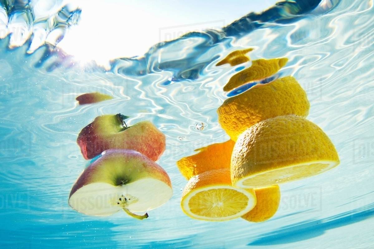 Fruit floating in swimming pool Stock Photo Dissolve