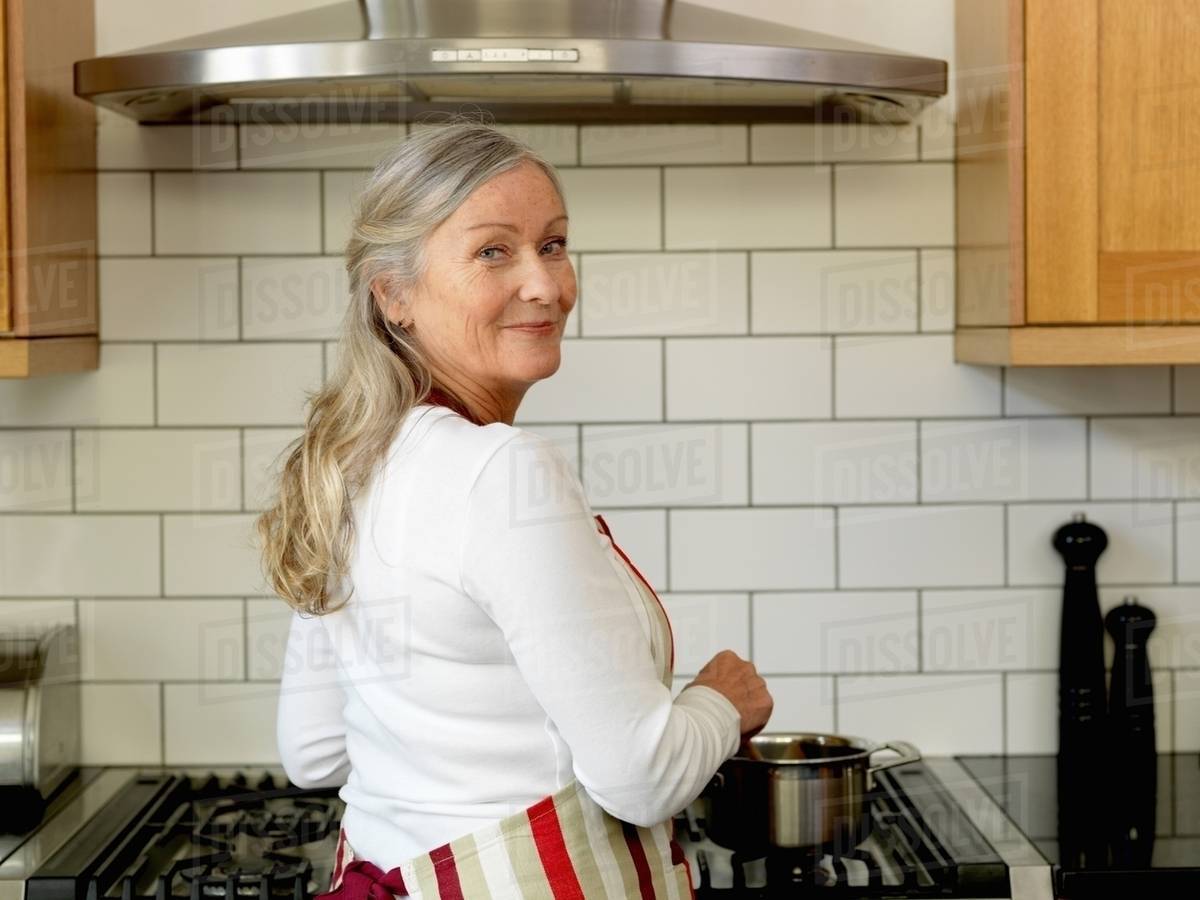 Older woman cooking in kitchen Stock Photo Dissolve