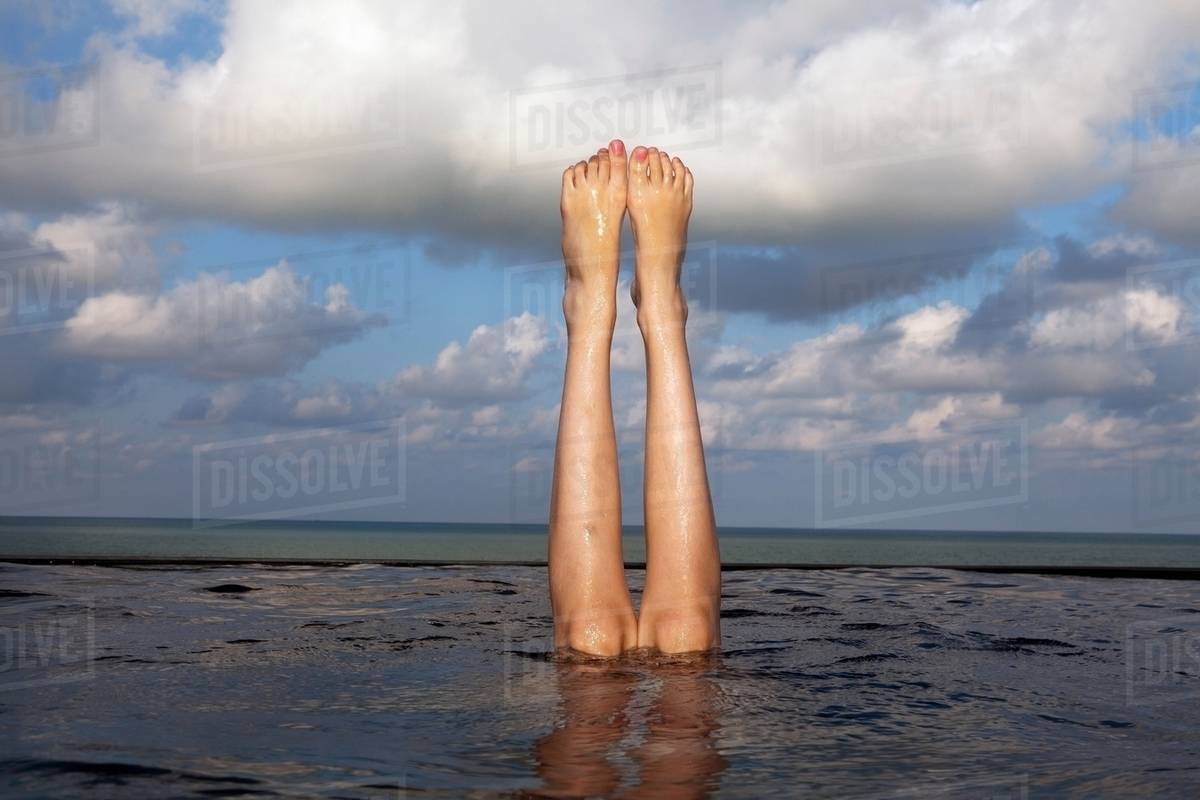 Legs sticking out of infinity pool Stock Photo Dissolve