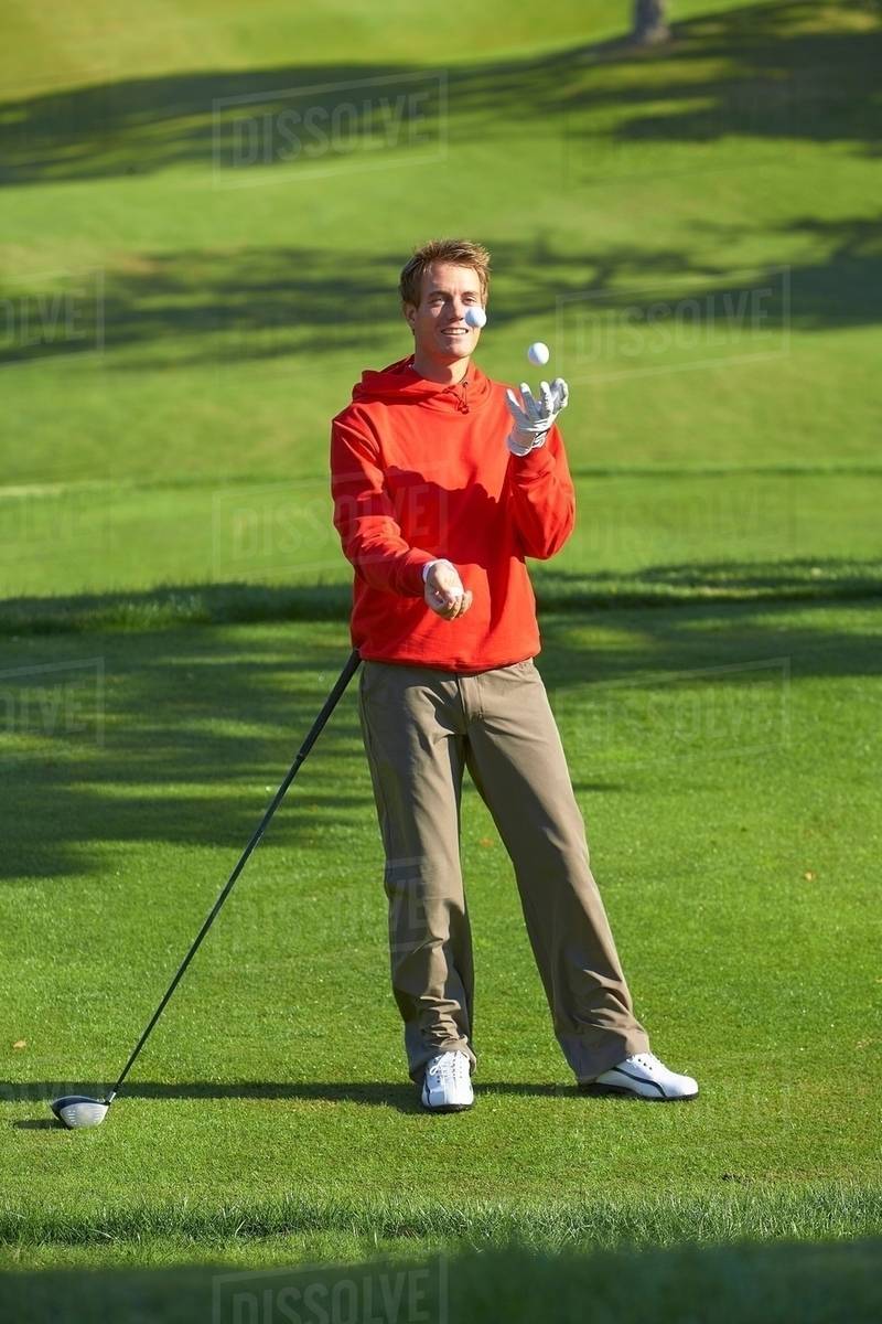 Full length front view of golfer juggling golf balls smiling Stock