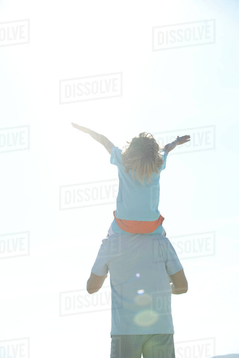 Boy riding on father's shoulders, rear view - Royalty-free Stock Photo ...