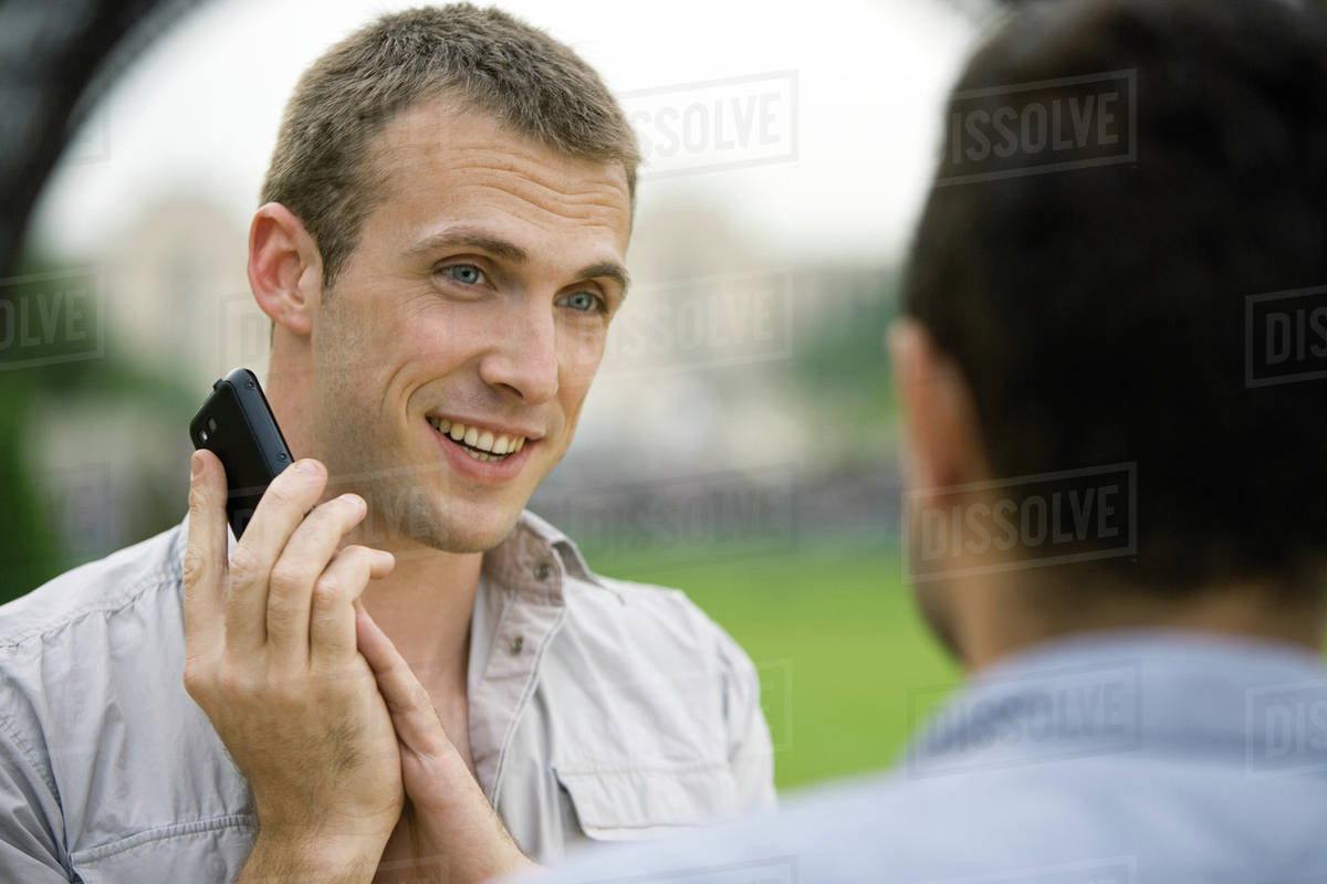 Man on phone call, covering cellphone mouthpiece with hand to talk to