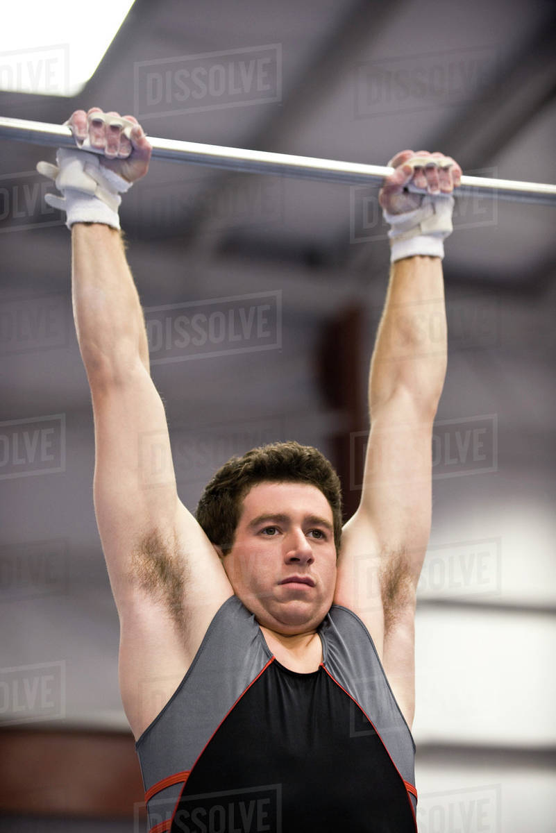 Male gymnast hanging from horizontal bar Stock Photo Dissolve