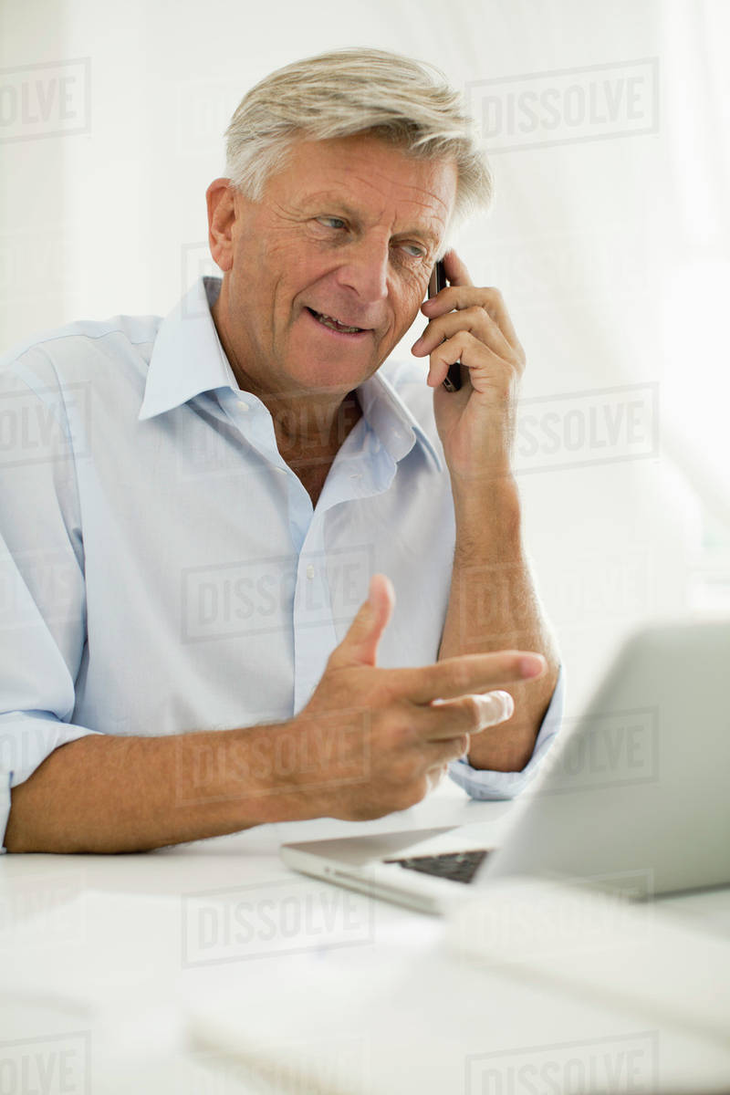 Man talking on cell phone while using laptop computer - Stock Photo ...