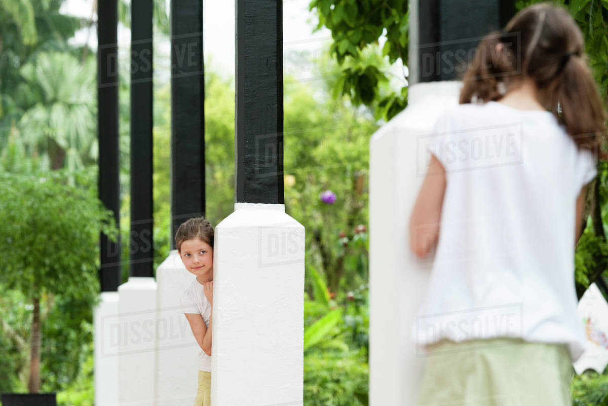 Girls playing hideandseek outdoors Stock Photo Dissolve